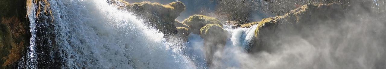 Powerful waterfall cascading over mossy rocks, creating a misty spray